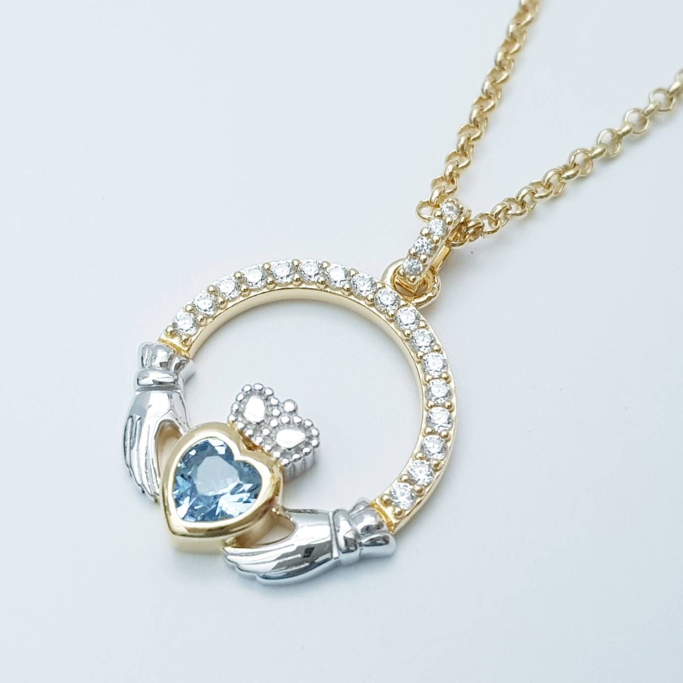Silver and gold claddagh pendant with Aquamarine blue stone