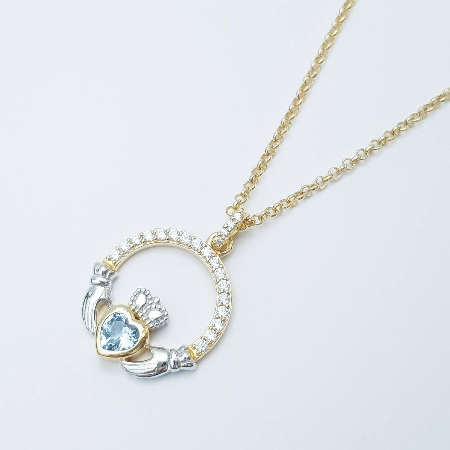 Silver and gold claddagh pendant with Aquamarine blue stone
