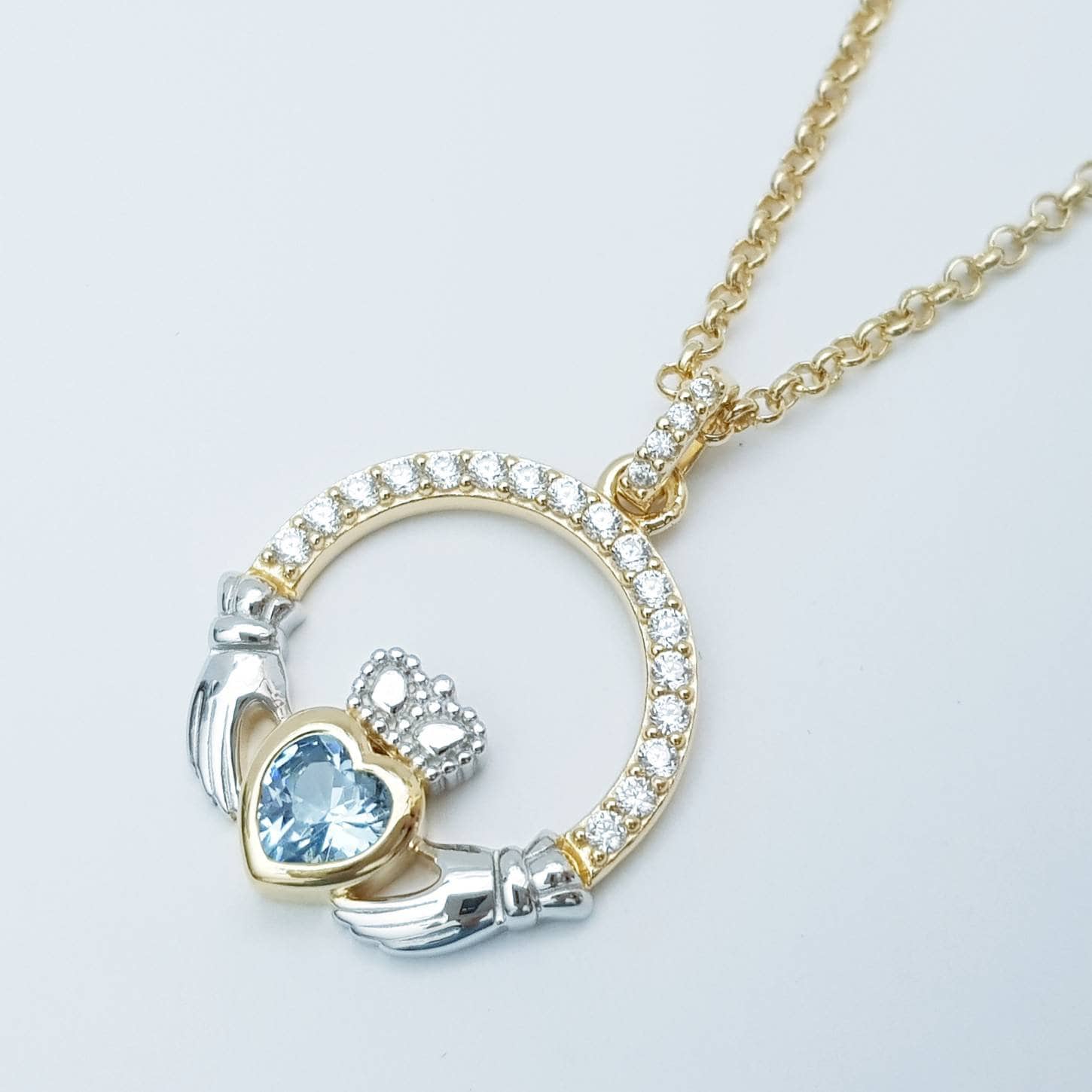 Silver and gold claddagh pendant with Aquamarine blue stone